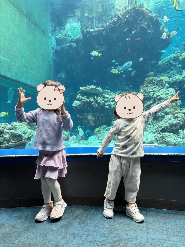 美ら海水族館の館内、色とりどりの魚が泳ぐ水槽と子どもたち