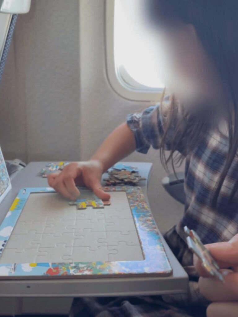 飛行機の機内でパズルを楽しむ女の子